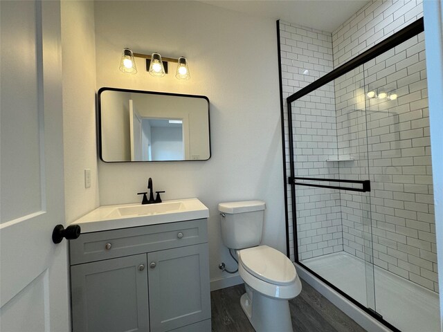 bathroom featuring toilet, vanity, wood-type flooring, and walk in shower