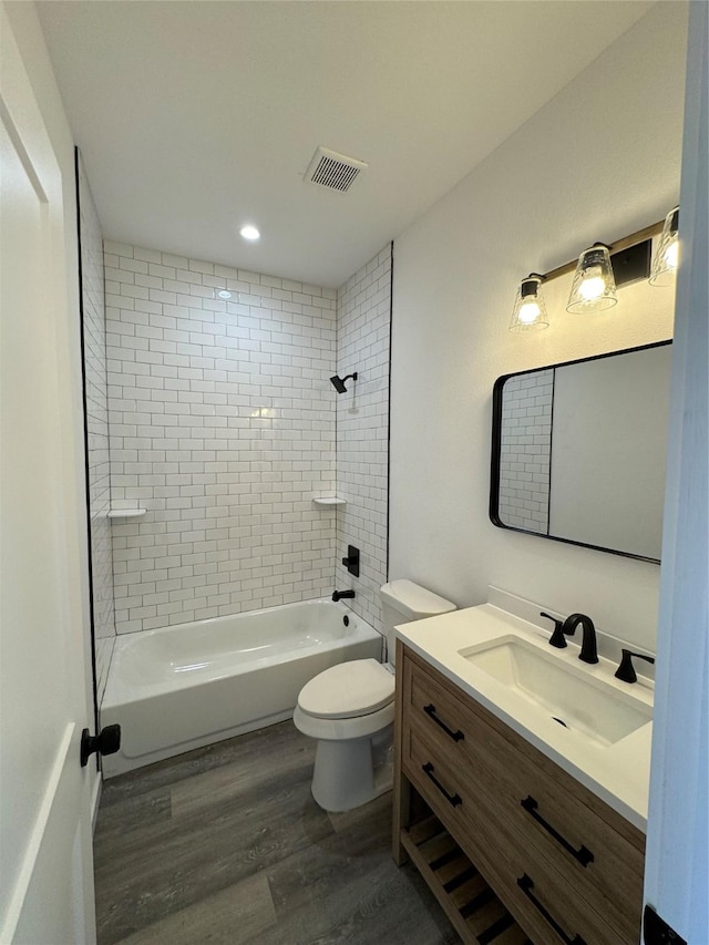 full bathroom with tiled shower / bath, toilet, vanity, and hardwood / wood-style flooring