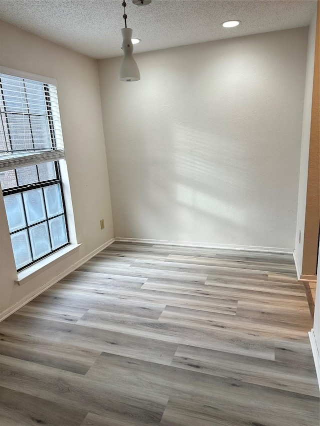 unfurnished room featuring a textured ceiling, light hardwood / wood-style floors, and a wealth of natural light