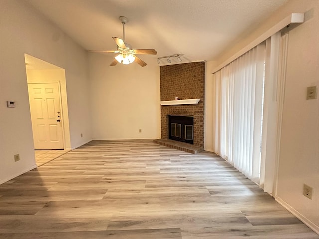 unfurnished living room with a fireplace, light wood-type flooring, and ceiling fan