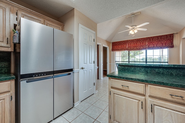 kitchen featuring stainless steel refrigerator, light brown cabinets, light tile patterned floors, a textured ceiling, and lofted ceiling