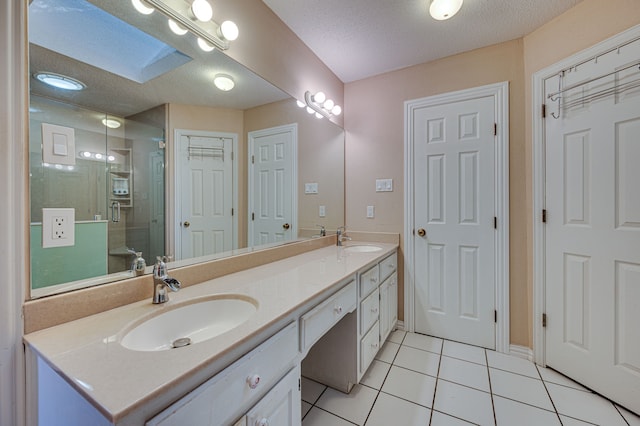 bathroom with a textured ceiling, a skylight, walk in shower, tile patterned floors, and vanity