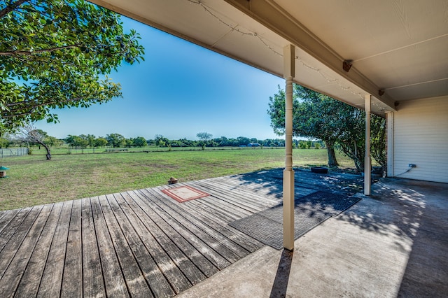 wooden terrace featuring a rural view, a yard, and a patio area