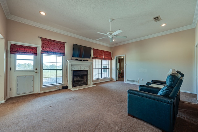 carpeted living room with a tile fireplace, ornamental molding, ceiling fan, and a wealth of natural light