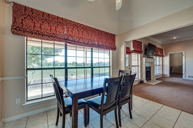 carpeted dining area featuring a textured ceiling, a tile fireplace, ornamental molding, and a healthy amount of sunlight