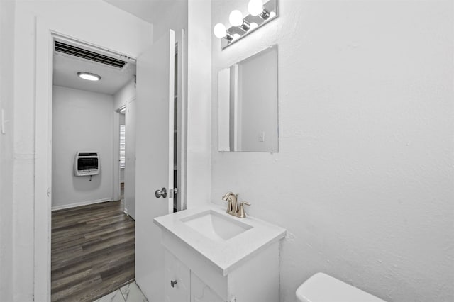 bathroom with wood-type flooring, vanity, toilet, and heating unit