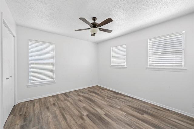 empty room featuring a textured ceiling, ceiling fan, and dark wood-type flooring