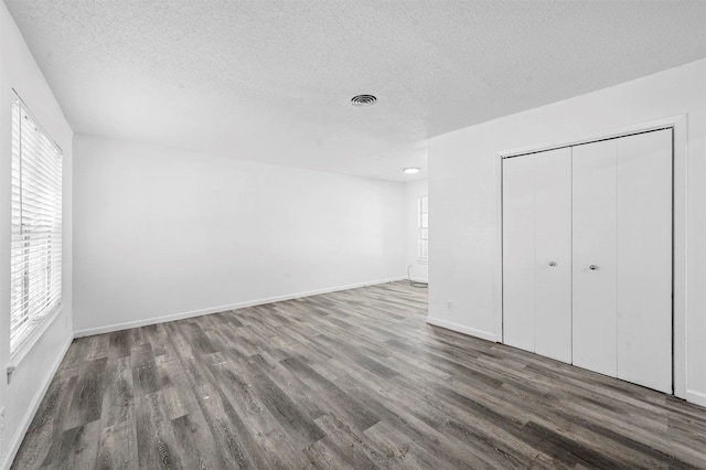 unfurnished bedroom featuring a textured ceiling, a closet, and dark hardwood / wood-style flooring