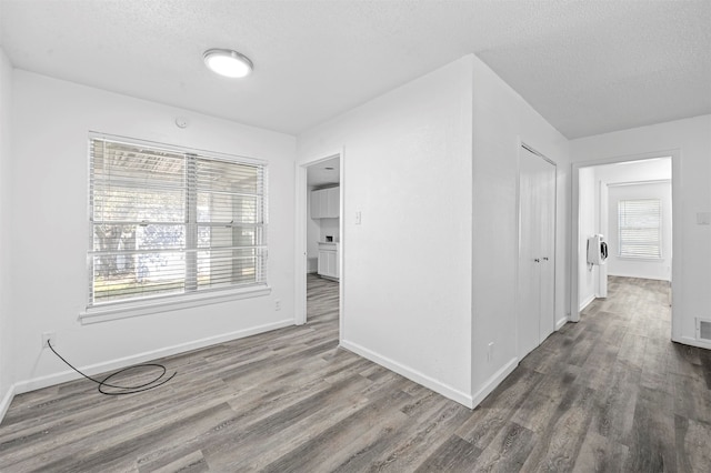 hall with a wealth of natural light, a textured ceiling, and hardwood / wood-style floors