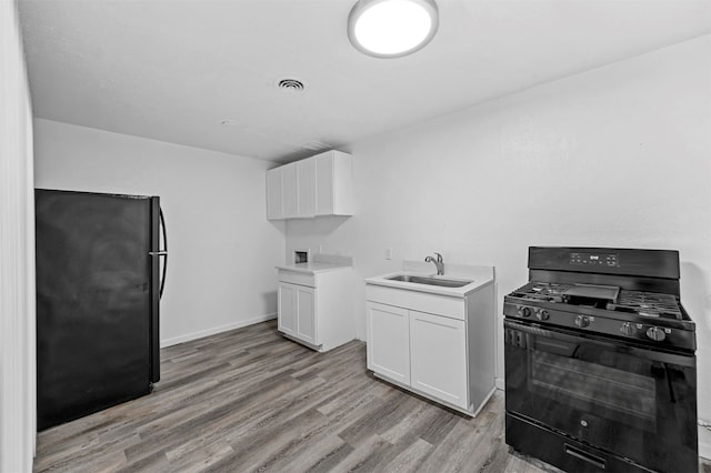 kitchen with light wood-type flooring, black appliances, sink, and white cabinets