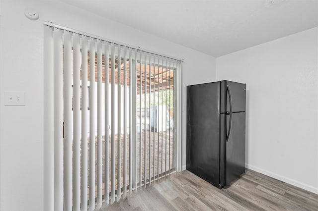 interior space with light hardwood / wood-style flooring and black refrigerator