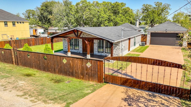 view of front of home with a fenced front yard, a shingled roof, central AC unit, a garage, and stone siding