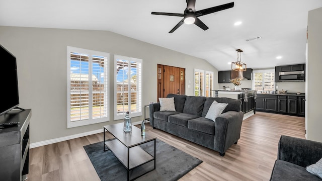 living area featuring lofted ceiling, baseboards, visible vents, and light wood-style floors