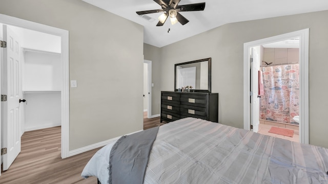 bedroom with ceiling fan, light wood-type flooring, ensuite bathroom, and lofted ceiling