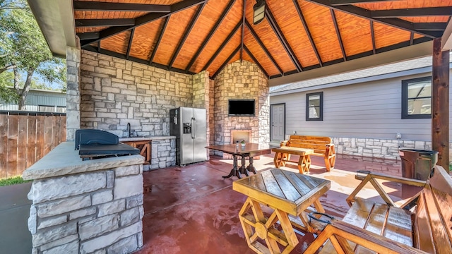 view of patio with area for grilling, fence, a gazebo, a fireplace, and a sink