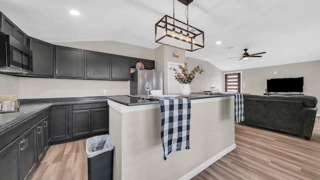 kitchen featuring lofted ceiling, light wood-style floors, dark countertops, and stainless steel appliances