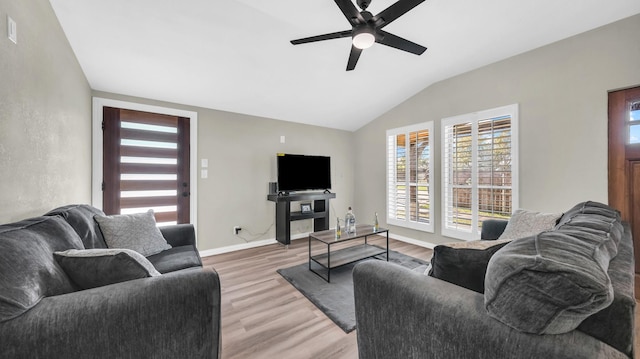 living room with lofted ceiling, light wood-style flooring, baseboards, and a ceiling fan