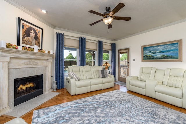 living room featuring a fireplace, a textured ceiling, ceiling fan, light hardwood / wood-style flooring, and ornamental molding