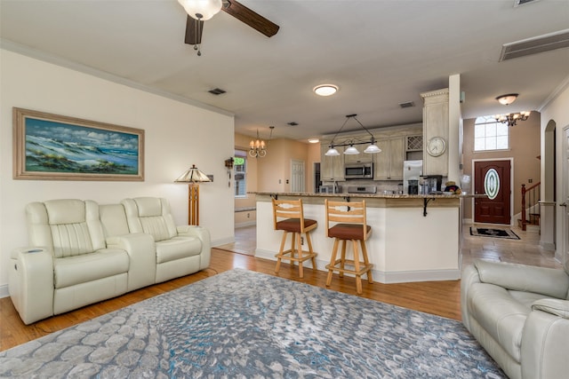 living room featuring ceiling fan with notable chandelier, light hardwood / wood-style floors, and crown molding