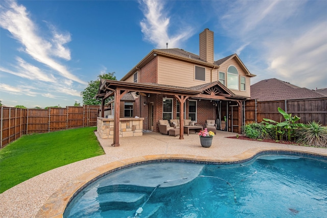 back of house featuring an outdoor living space, a yard, a patio, and a hot tub