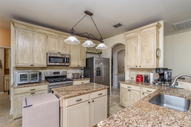 kitchen with light stone counters, sink, tasteful backsplash, decorative light fixtures, and appliances with stainless steel finishes