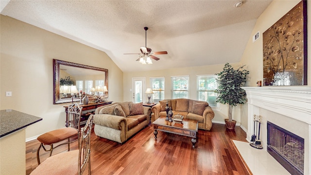 living room featuring hardwood / wood-style floors, ceiling fan, vaulted ceiling, and a textured ceiling