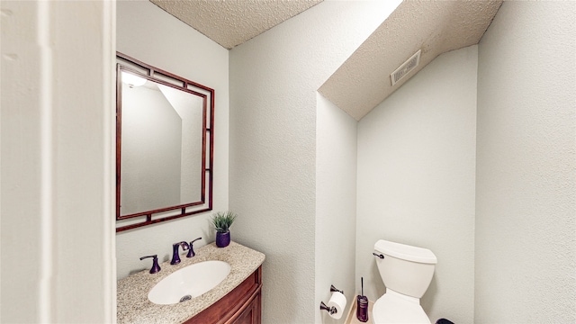 bathroom with vanity, toilet, and a textured ceiling