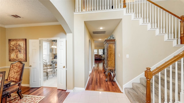 entrance foyer with wood-type flooring, ornamental molding, and a textured ceiling