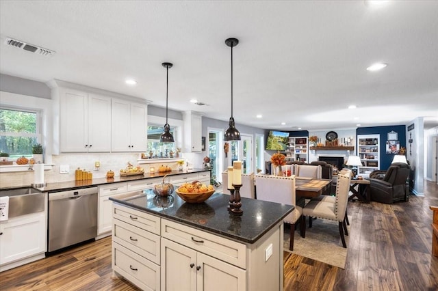 kitchen with pendant lighting, stainless steel dishwasher, a fireplace, visible vents, and open floor plan