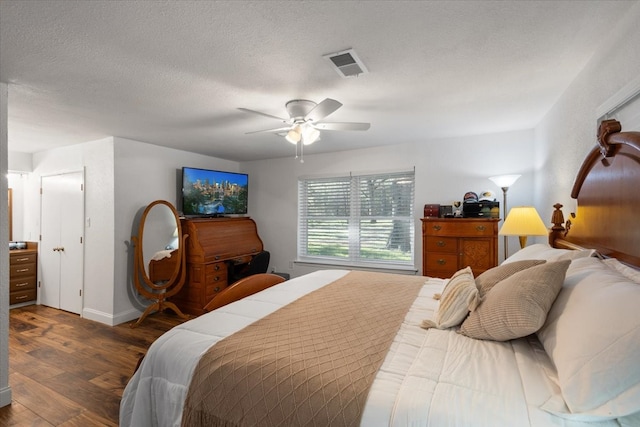 bedroom with ceiling fan, dark hardwood / wood-style floors, and a textured ceiling