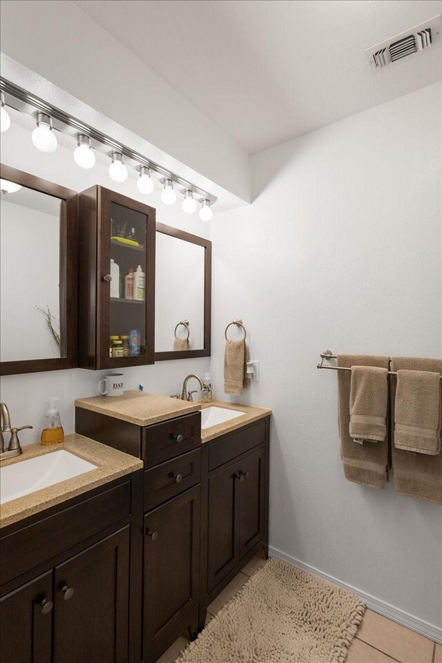 bathroom featuring a sink, visible vents, tile patterned floors, and double vanity
