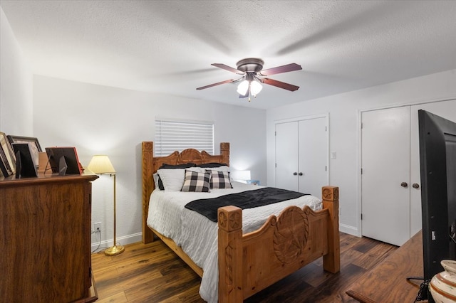 bedroom featuring a textured ceiling, two closets, dark hardwood / wood-style floors, and ceiling fan