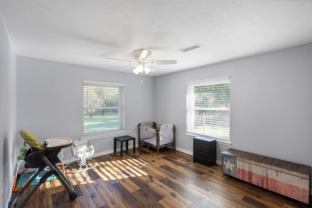 living area featuring ceiling fan, dark wood-type flooring, and plenty of natural light