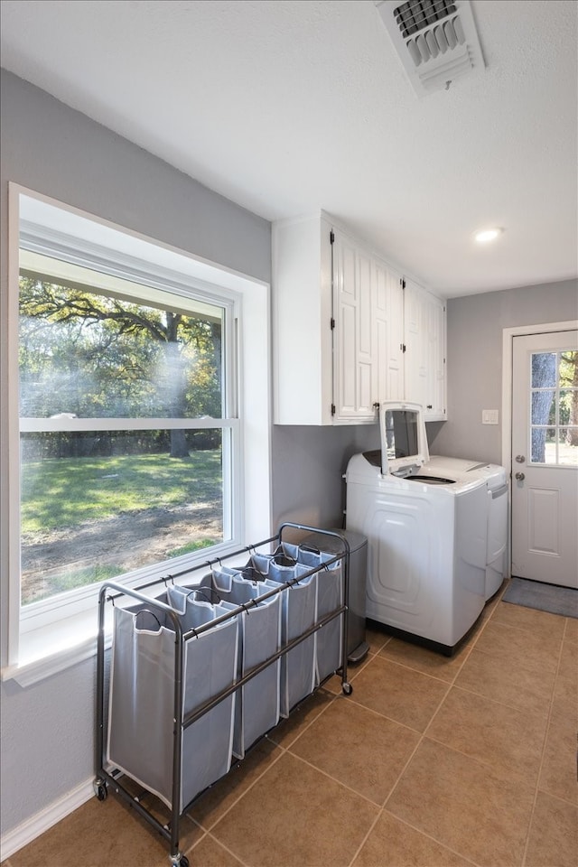 clothes washing area with cabinets, dark tile patterned flooring, and independent washer and dryer