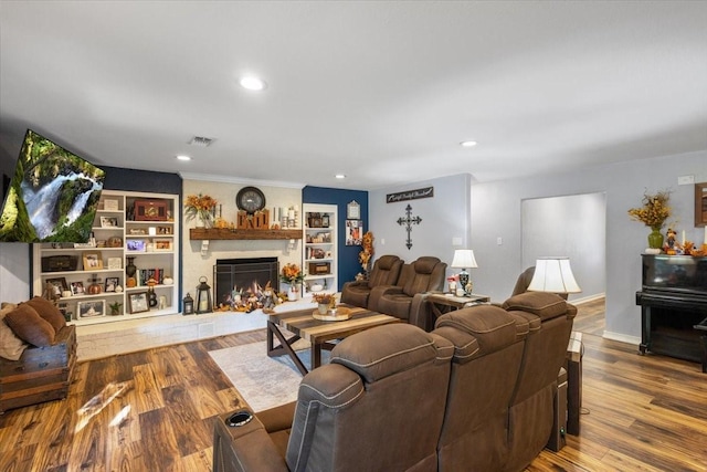 living area featuring built in features, recessed lighting, a fireplace, visible vents, and wood finished floors