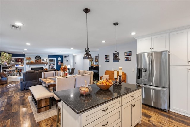 kitchen with pendant lighting, dark stone countertops, dark hardwood / wood-style floors, and stainless steel fridge