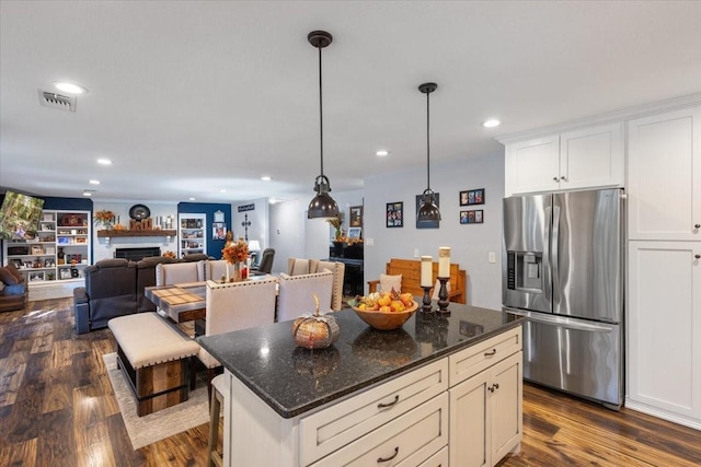 kitchen featuring dark wood finished floors, a fireplace, stainless steel fridge, and visible vents