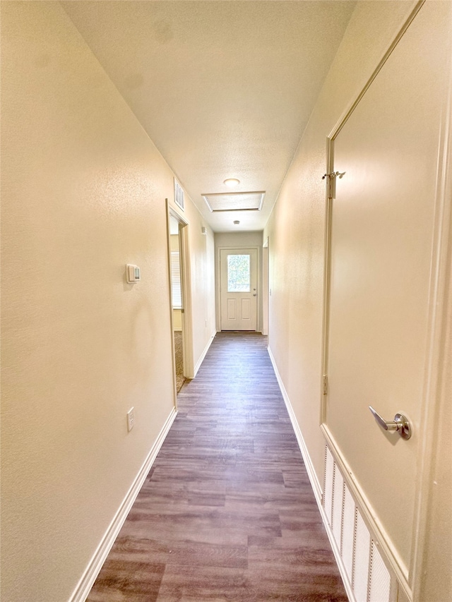 hallway with a textured ceiling and hardwood / wood-style floors