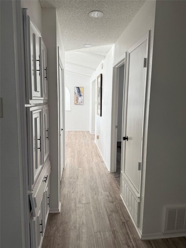 hall featuring hardwood / wood-style flooring, a textured ceiling, and vaulted ceiling