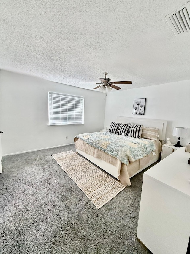 bedroom with ceiling fan, dark carpet, and a textured ceiling