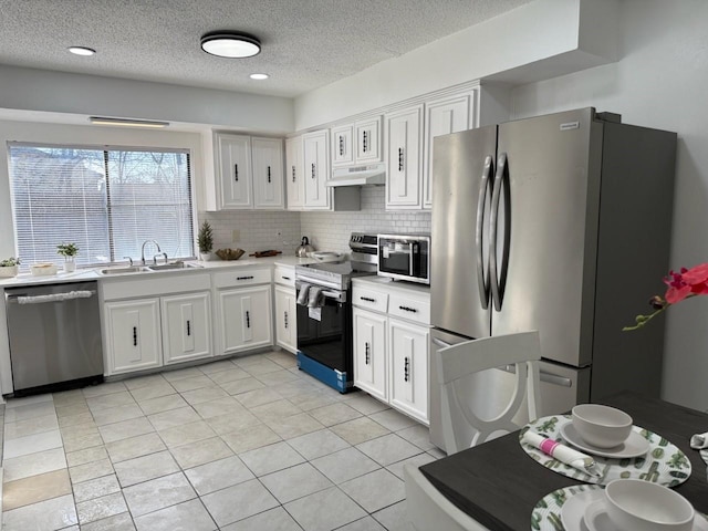 kitchen featuring decorative backsplash, a textured ceiling, stainless steel appliances, sink, and white cabinets