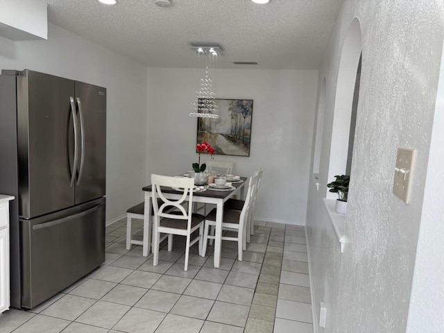 dining area with light tile patterned floors, a chandelier, and a textured ceiling