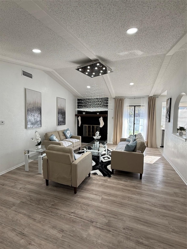 living room featuring lofted ceiling, a large fireplace, a textured ceiling, and hardwood / wood-style flooring