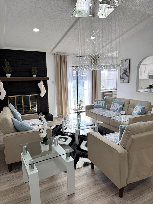 living room featuring hardwood / wood-style flooring, a notable chandelier, a fireplace, and a textured ceiling