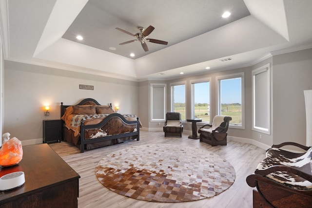 bedroom featuring crown molding, light hardwood / wood-style floors, a tray ceiling, and ceiling fan