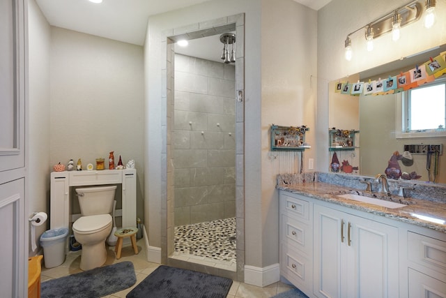 bathroom with a tile shower, vanity, toilet, and tile patterned floors