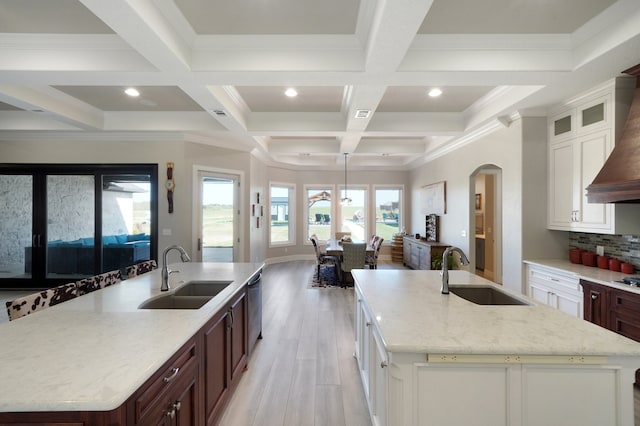 kitchen with light hardwood / wood-style floors, a large island with sink, backsplash, and sink