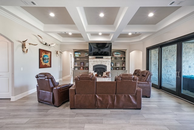 living room featuring light hardwood / wood-style flooring, beamed ceiling, coffered ceiling, and a stone fireplace