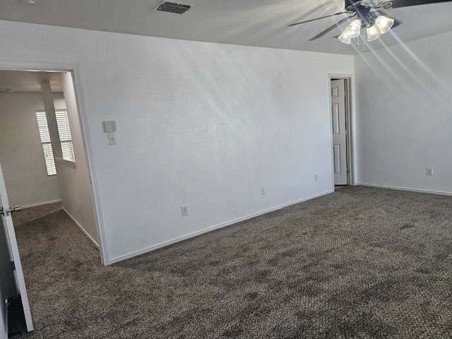 spare room with dark colored carpet and ceiling fan