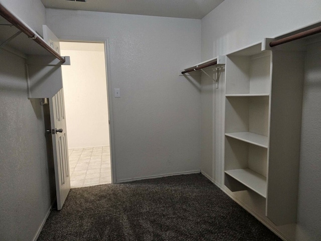 walk in closet with dark carpet